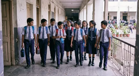 Indian school students walking through a school corridor in matching navy and white uniforms with ties